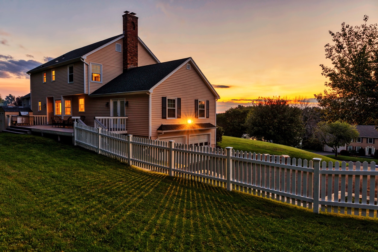 Beautiful colonial American house at sunset with white picket fence